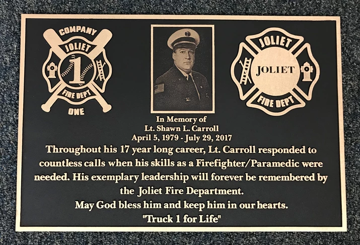 Large bronze memorial plaque with a photo and logos