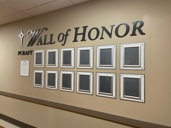 Immersive environmental branding displaying legacy and achievement through premium routing, layered acrylics, and dimensional text typography.
