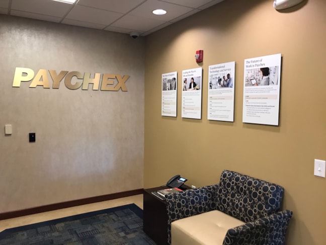 Complete corporate lobby environmental branding integrating architectural dimensional letters and professional media frames. 