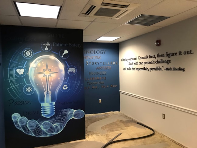 A custom vinyl wall mural featuring a glowing digital lightbulb graphic symbolizing medical innovation and ideas.