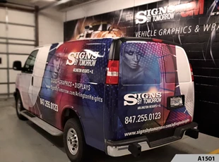 Our Cargo Van fully wrapped, parked in our in front of large wall mural; vinyl graphics installed on cinder block wall.