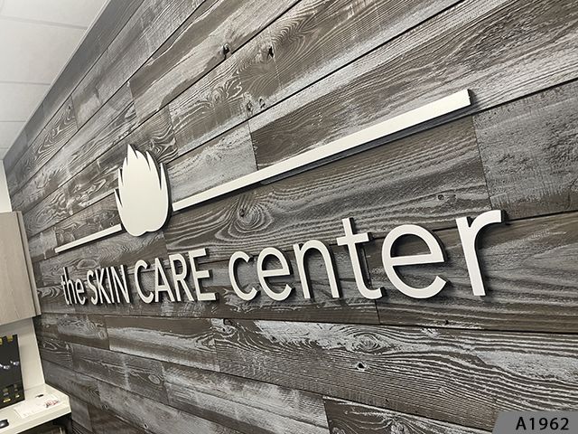 3D Letters and 3D Logo with Brushed Aluminum Metal Faces and black Returns stud-mounted to textured Lobby Wall 